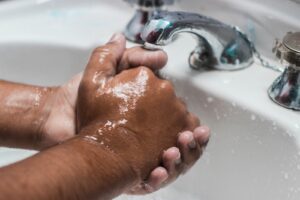 Peronne qui se lave les mains à l'évier